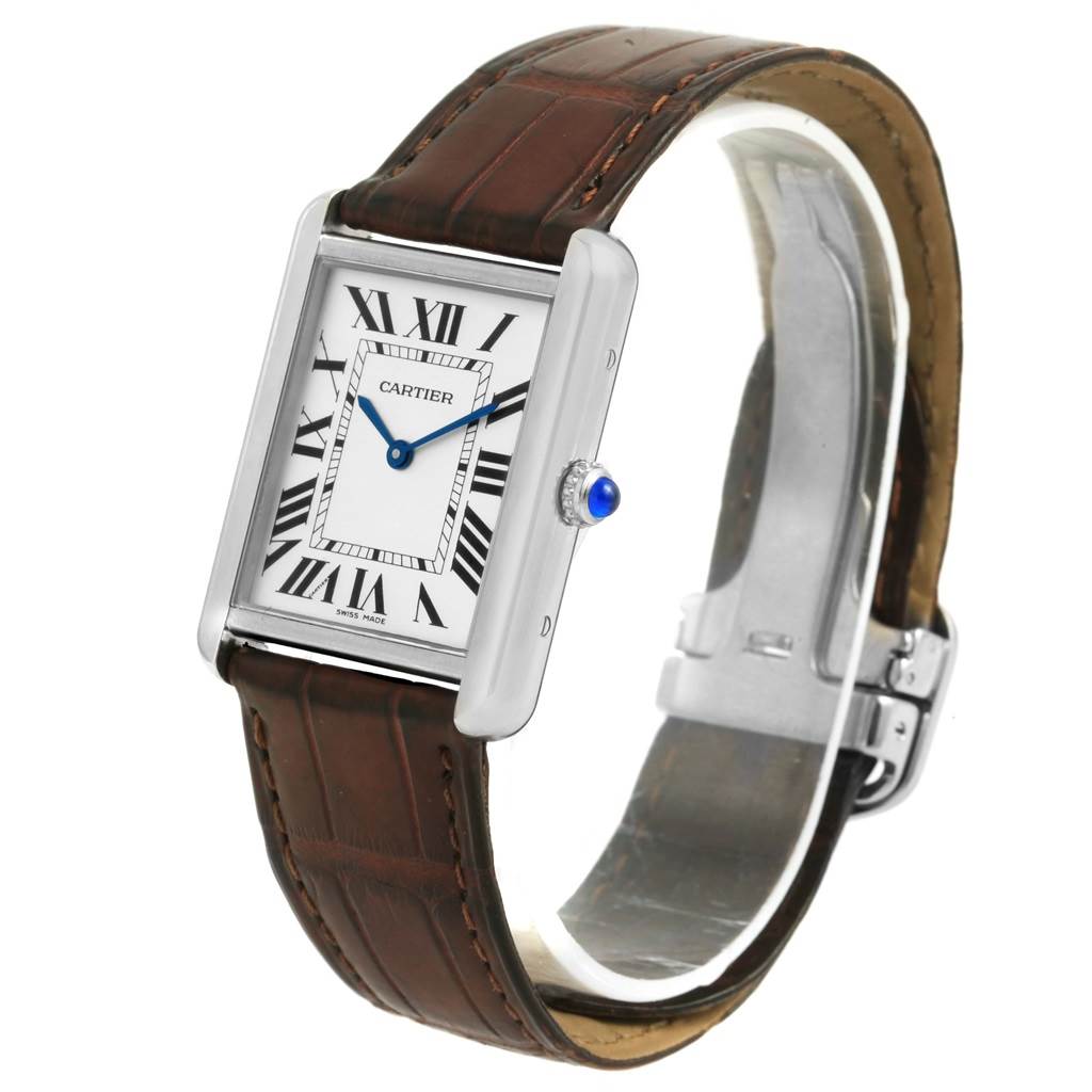 The Tank Solo by Cartier is shown at a three-quarter angle, highlighting its rectangular face, Roman numerals, blue hands, crown, and brown leather strap.