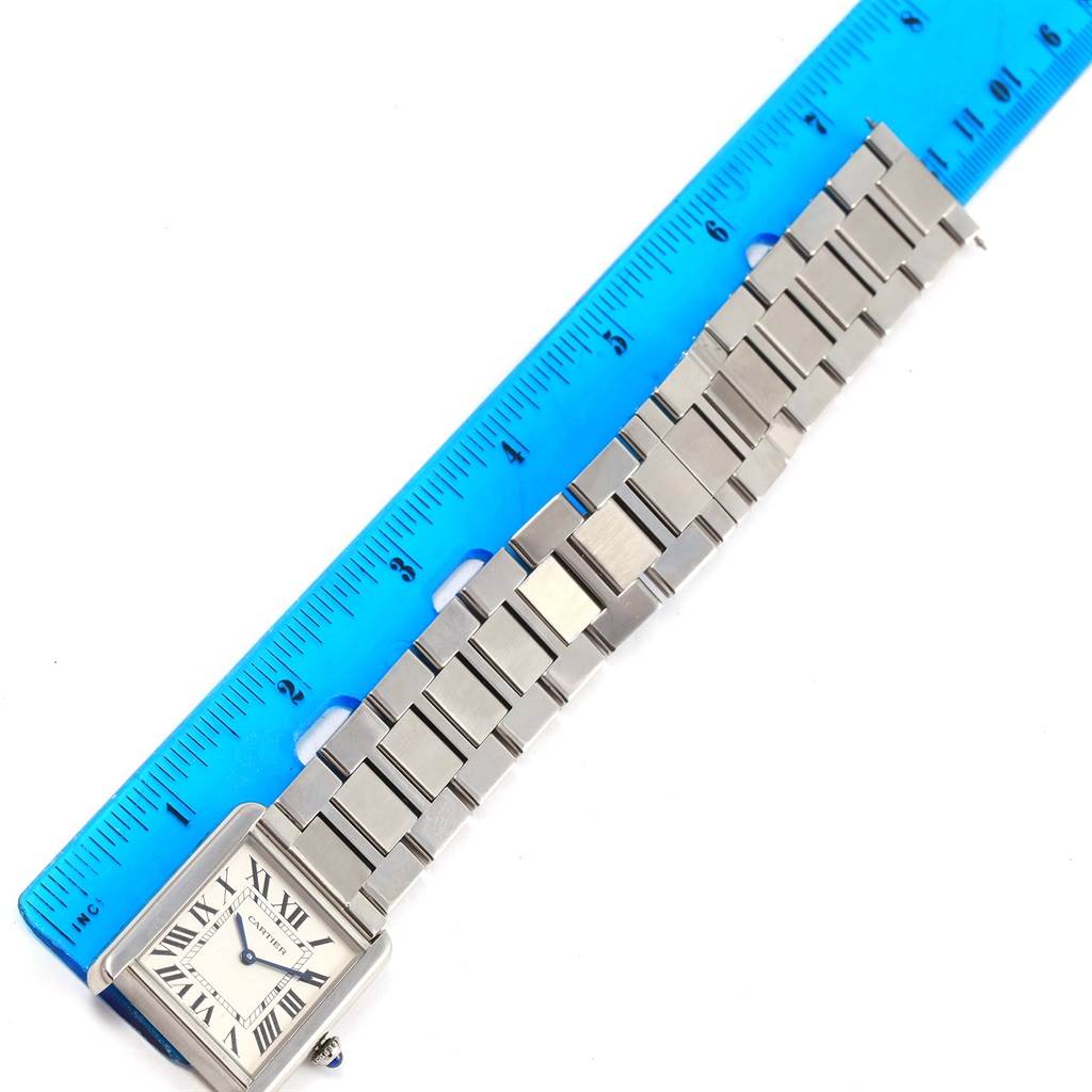 The image shows the Cartier Tank Solo W5200014 Stainless Steel Silver Dial W5200014 Stainless Steel Silver Dial watch
s face and metal bracelet next to a blue ruler for scale.
