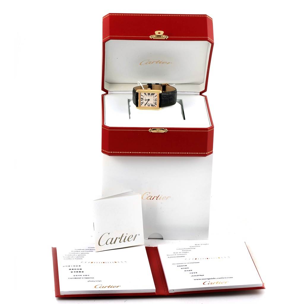 This image shows a Tank Solo by Cartier watch inside a red presentation box with accompanying booklets in the foreground.