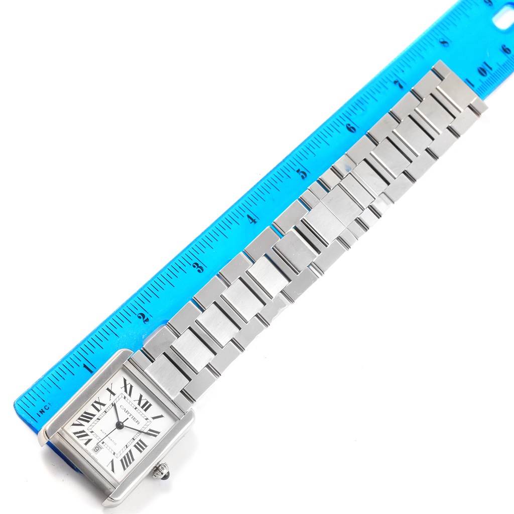 The image shows a Tank Solo watch by Cartier lying flat with its stainless steel bracelet measured against a blue ruler.