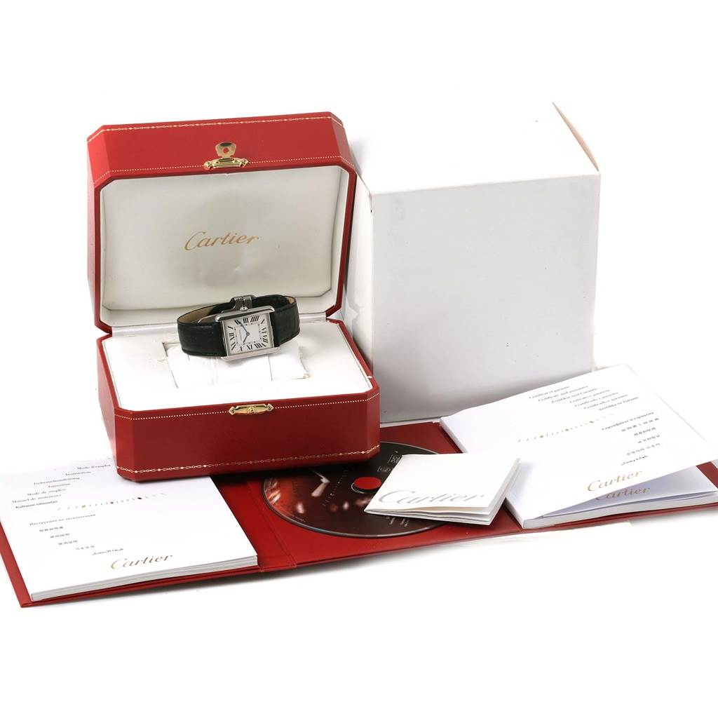 The image shows a Cartier Tank Solo W1018355 Stainless Steel Silver Dial W1018355 Stainless Steel Silver Dial watch in its open box surrounded by booklets and a CD.