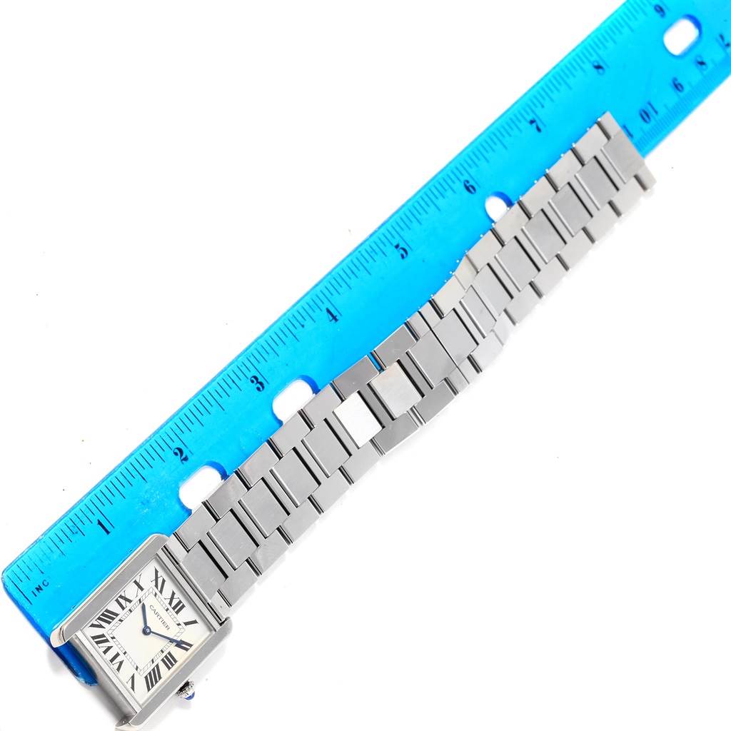 The image shows a Cartier Tank Solo W5200014 Men
s Stainless Steel Silver Dial W5200014 Men
s Stainless Steel Silver Dial watch laid flat next to a blue ruler, displaying the face and metal bracelet.