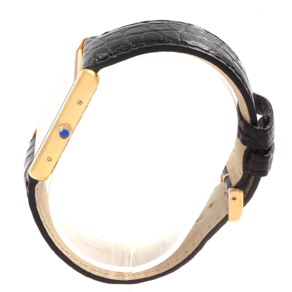 This side view of the Cartier Tank Solo W1018855 Steel and Gold (two tone) Silver Dial W1018855 Steel and Gold (two tone) Silver Dial watch shows its black leather strap, gold case, and crown with a blue gem.