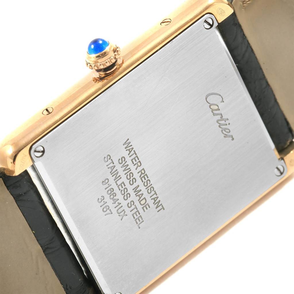 The image shows the back case and crown of a Cartier Tank Solo W1018855 Men
s Steel and Gold (two tone) Silver Dial W1018855 Men
s Steel and Gold (two tone) Silver Dial watch, highlighting its inscription and blue cabochon crown.