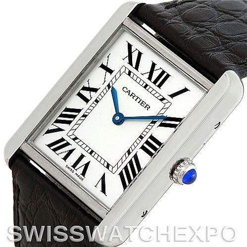 The image shows a Cartier Tank Solo W1018355 Men
s Stainless Steel Silver Dial W1018355 Men
s Stainless Steel Silver Dial watch at an angled top view, displaying the face, bezel, partial strap, and crown with a blue cabochon.