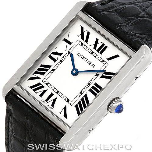 The image displays a Cartier Tank Solo W1018355 Men
s Stainless Steel Silver Dial W1018355 Men
s Stainless Steel Silver Dial watch at an angled view, highlighting its rectangular face, leather strap, and blue cabochon crown.