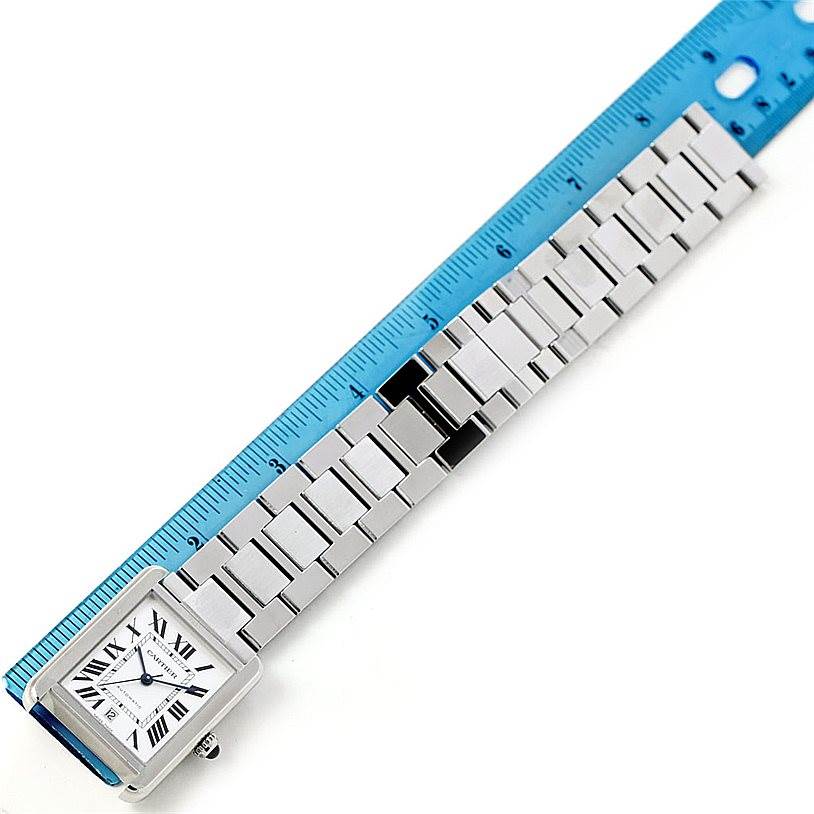 The image shows the top view of the Cartier Tank Solo W5200028 Men
s Stainless Steel Silver Dial W5200028 Men
s Stainless Steel Silver Dial watch, focusing on the bracelet and face adjacent to a blue ruler.