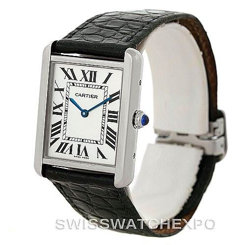 A Cartier Tank Solo W1018355 Men
s Stainless Steel Silver Dial W1018355 Men
s Stainless Steel Silver Dial watch is shown at an angle highlighting the rectangular face, Roman numeral dial, crown with blue cabochon, and black leather strap.