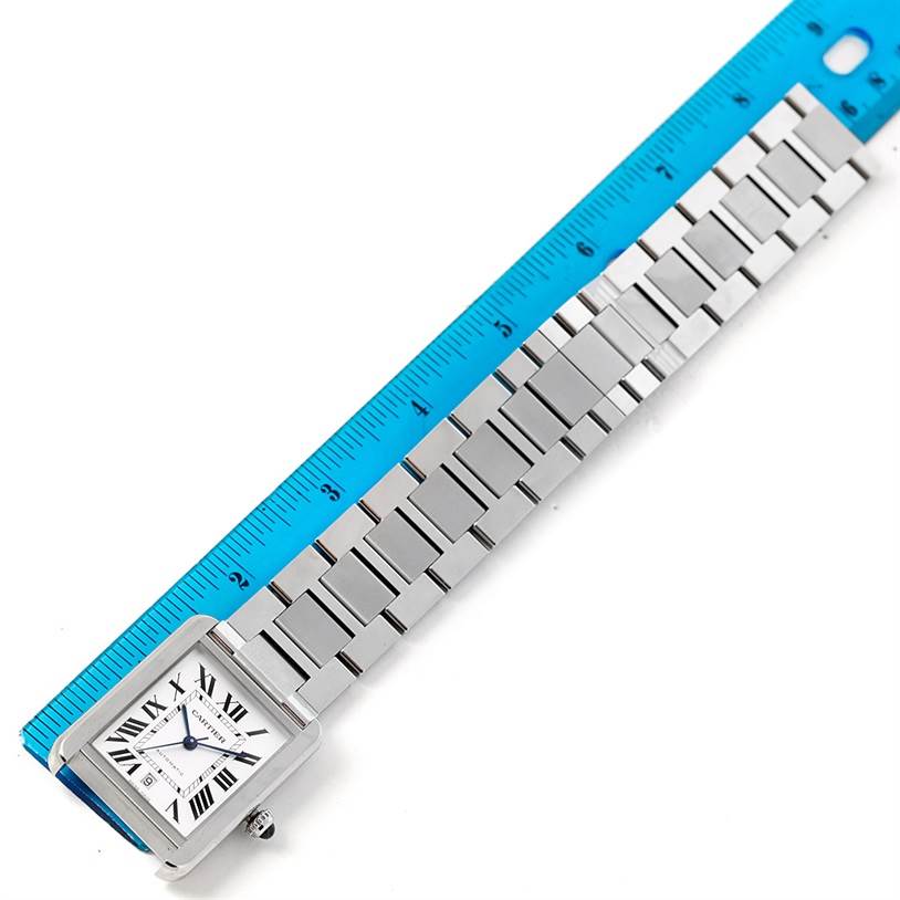 The Cartier Tank Solo W5200028 Men
s Stainless Steel Silver Dial W5200028 Men
s Stainless Steel Silver Dial watch is shown from an above angle, displaying its rectangular face and metal bracelet next to a blue ruler.