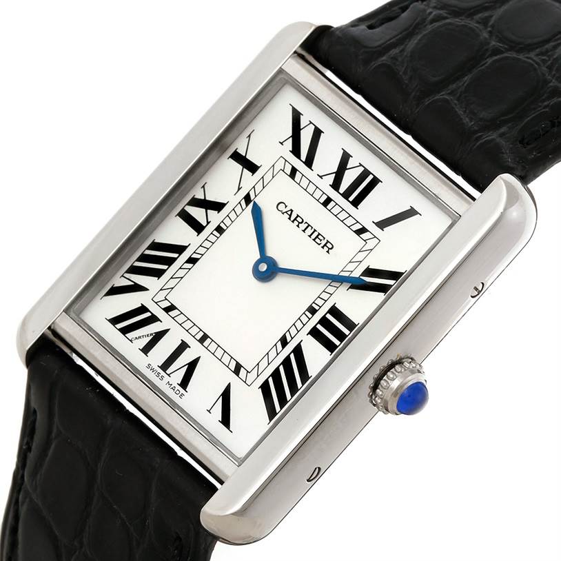 The image shows a Cartier Tank Solo W1018355 Men
s Stainless Steel Silver Dial W1018355 Men
s Stainless Steel Silver Dial watch from an angled top view, highlighting its Roman numeral dial, blue hands, and crown with a blue cabochon. 