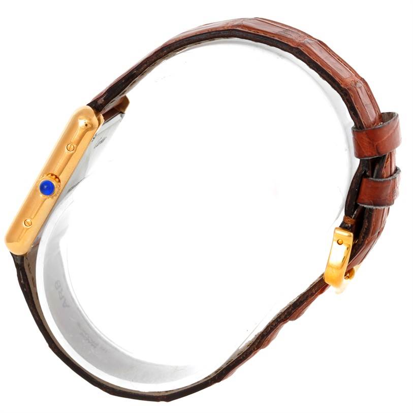 The Cartier Tank Solo W1018755 Women's Steel and Gold (two tone) Silver Dial W1018755 Women's Steel and Gold (two tone) Silver Dial watch is shown from a side angle, displaying its gold casing, blue cabochon crown, and brown leather strap.