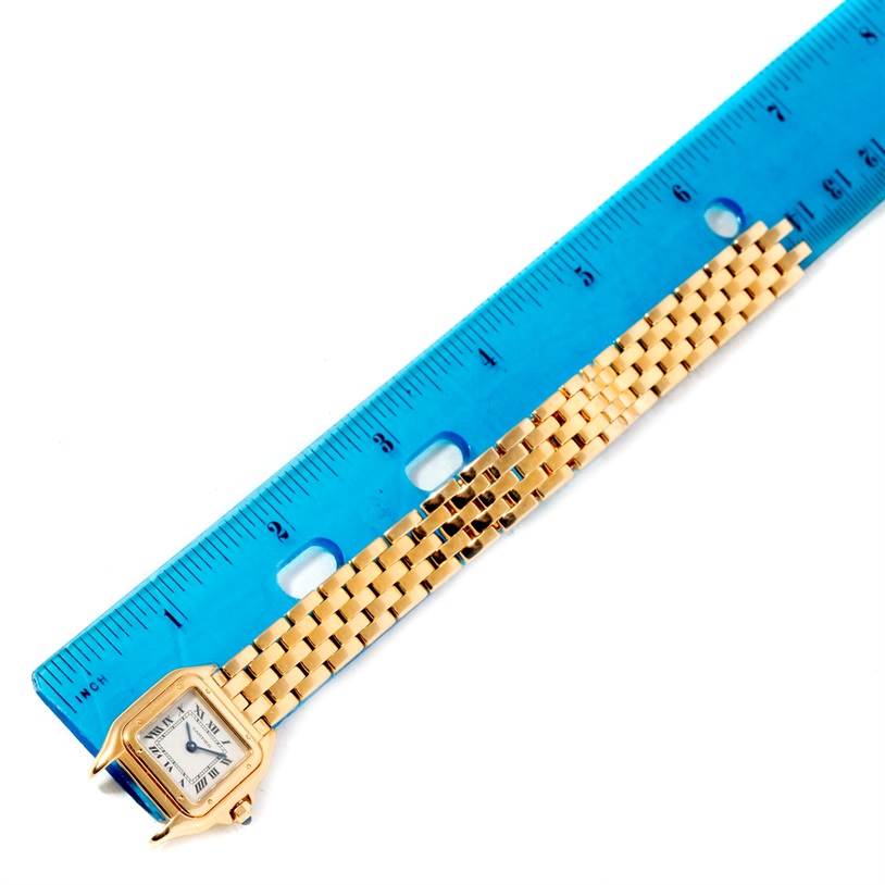 The image shows a top-down view of a Panthère de Cartier watch with a gold bracelet next to a blue ruler for scale.