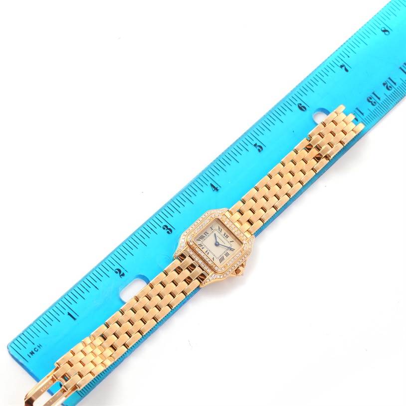 This image shows a Cartier Panthere WF3072B9 Women's Yellow Gold Silver Dial WF3072B9 Women's Yellow Gold Silver Dial watch laid flat and measured adjacent to a blue ruler, highlighting the watch's face and band.