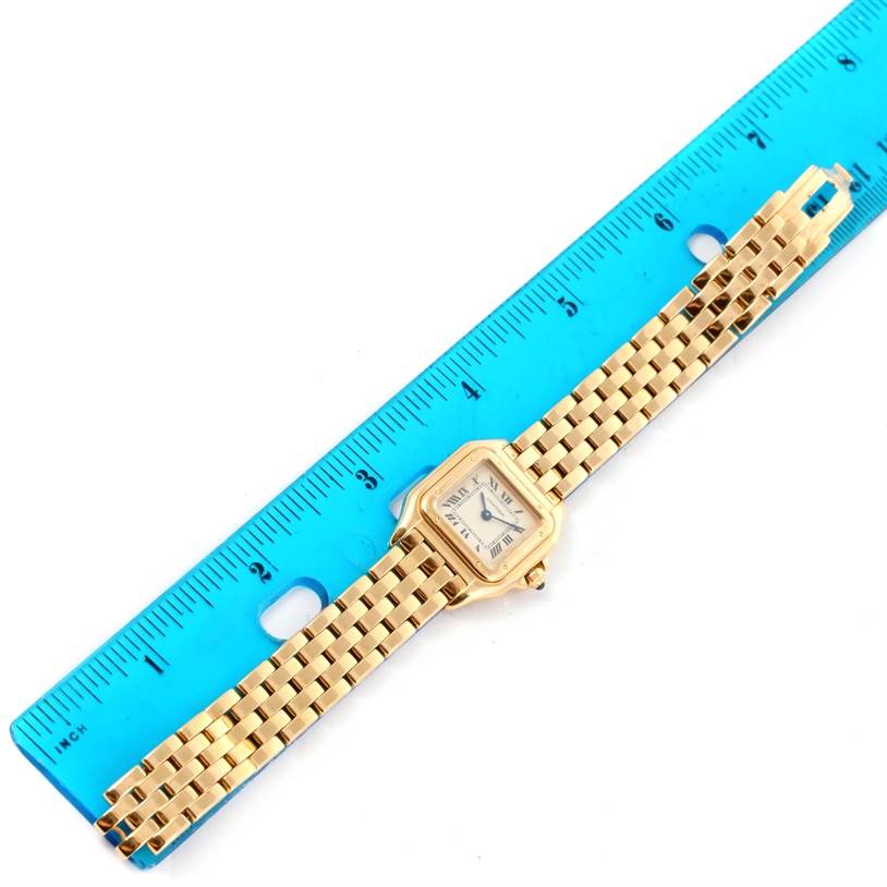 The Cartier Panthere W25022B9 Women's Yellow Gold Silver Dial W25022B9 Women's Yellow Gold Silver Dial watch is photographed from above, showing its full face and band, next to a blue ruler.