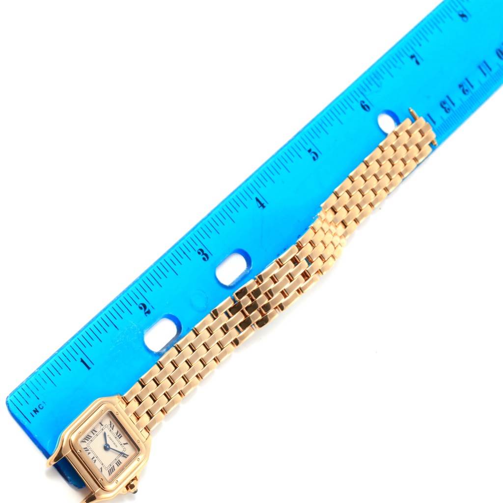 The image shows an overhead view of a Cartier Panthere W25022B9 Women's Yellow Gold Beige Dial W25022B9 Women's Yellow Gold Beige Dial watch with a gold chain bracelet next to a blue ruler.