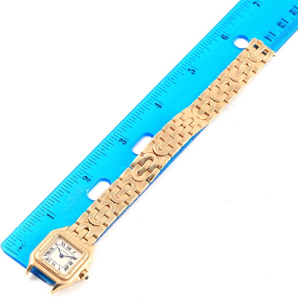 The image shows a Panthere model by Cartier watch laid flat next to a blue ruler, displaying the wristband and watch face.