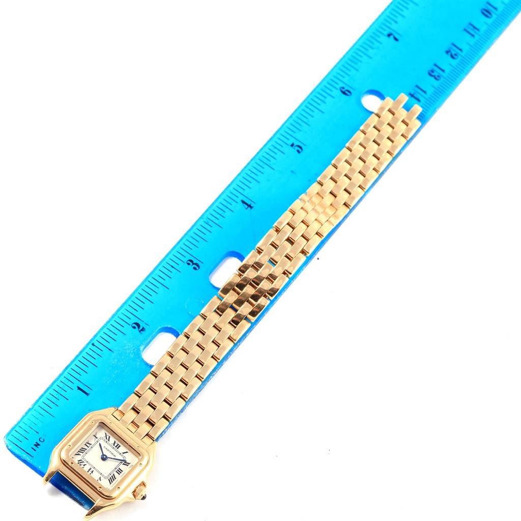 The image shows a Panthere de Cartier watch with a gold bracelet placed next to a blue ruler for scale.