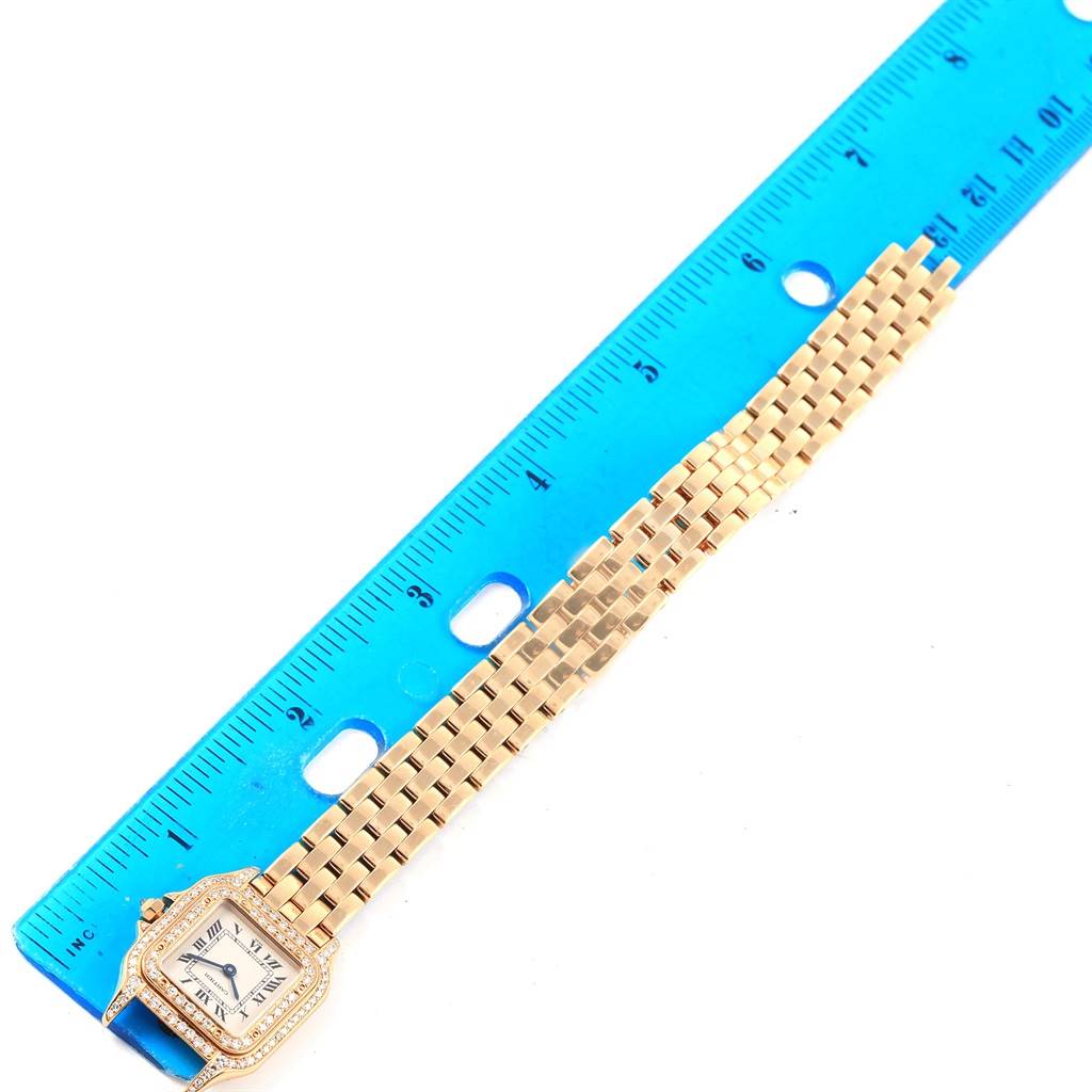 The image shows a Cartier Panthère watch laid next to a blue ruler, displaying the face and the full length of the bracelet.