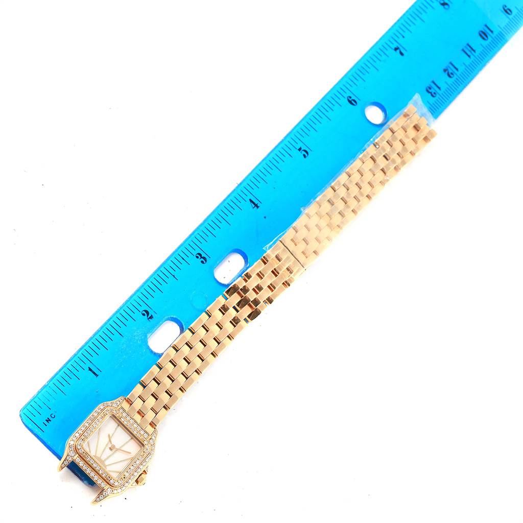 The Cartier Panthere 86691 Women's Yellow Gold Mother of Pearl Dial 86691 Women's Yellow Gold Mother of Pearl Dial watch is shown from a top-down angle with the face and part of the gold bracelet visible next to a ruler.