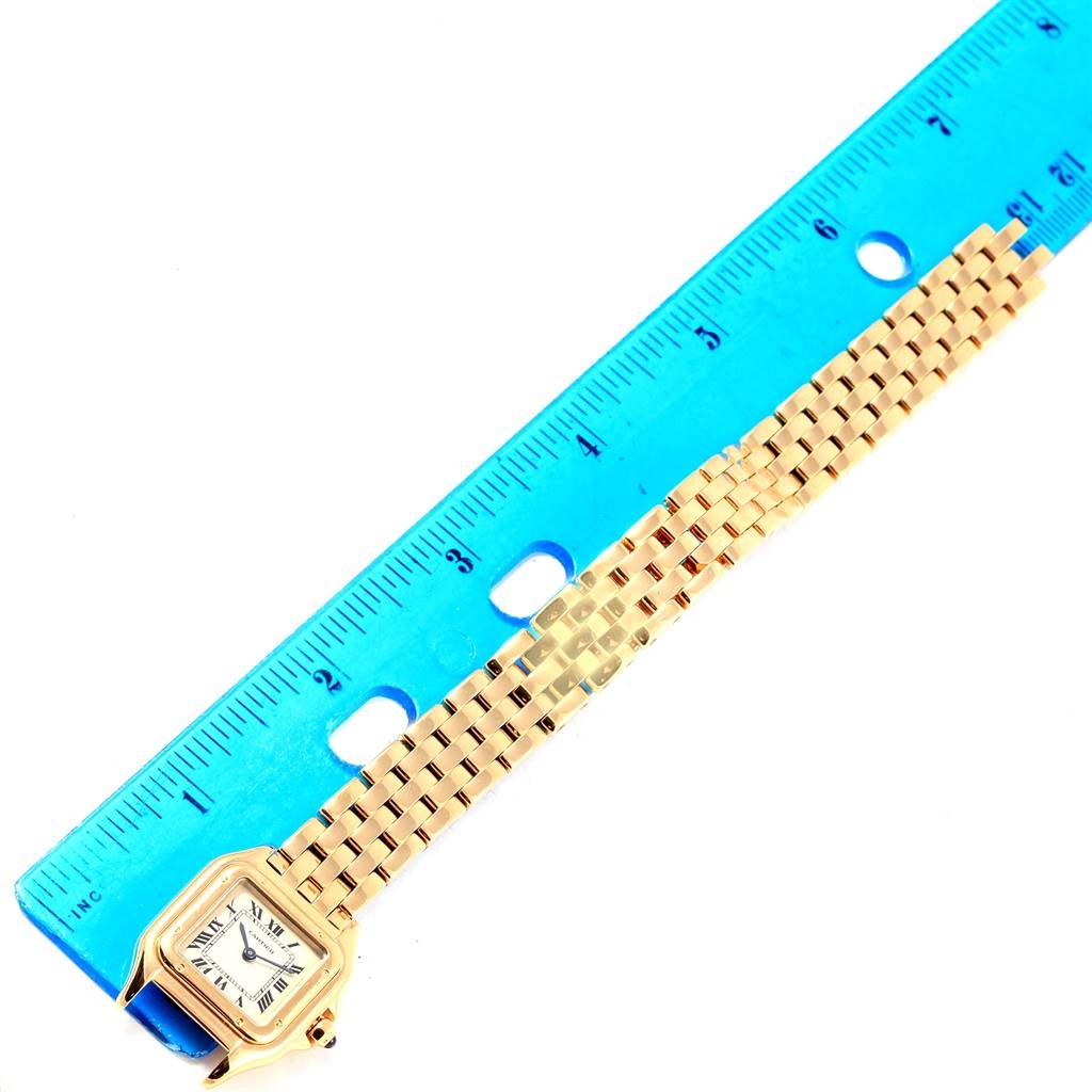 The Panthere model by Cartier is shown flat with the face visible alongside a blue ruler for scale.