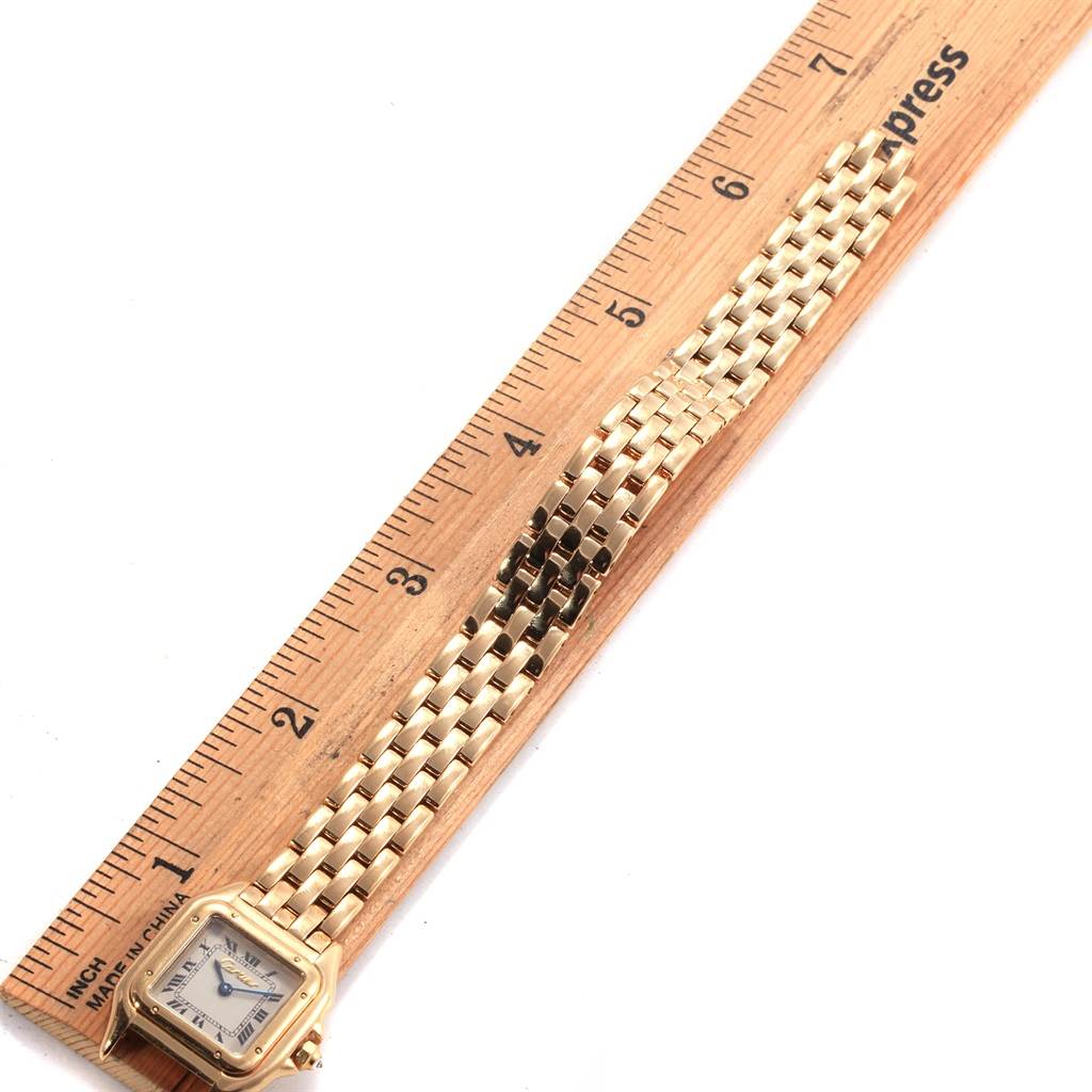 The Cartier Panthere W25022B9 Women's Yellow Gold Silver Dial W25022B9 Women's Yellow Gold Silver Dial watch is shown from a top-down angle with its gold bracelet beside a ruler for measurement.