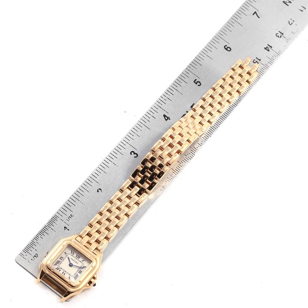 The Cartier Panthere W25022B9 Women's Yellow Gold Silver Dial W25022B9 Women's Yellow Gold Silver Dial watch is positioned flat with its gold bracelet extended next to a ruler for measurement.