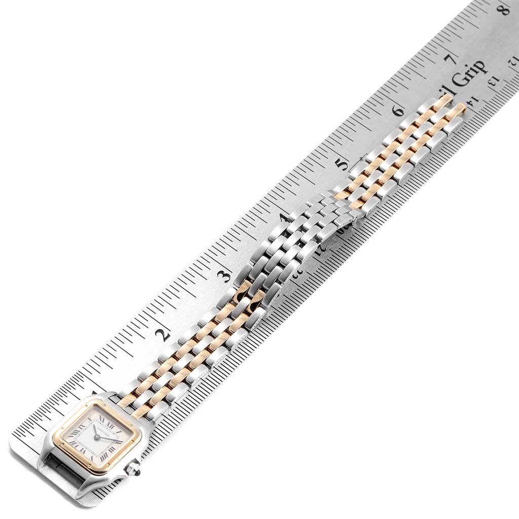 The image shows a Panthere de Cartier watch with a two-tone bracelet, placed diagonally against a metal ruler.