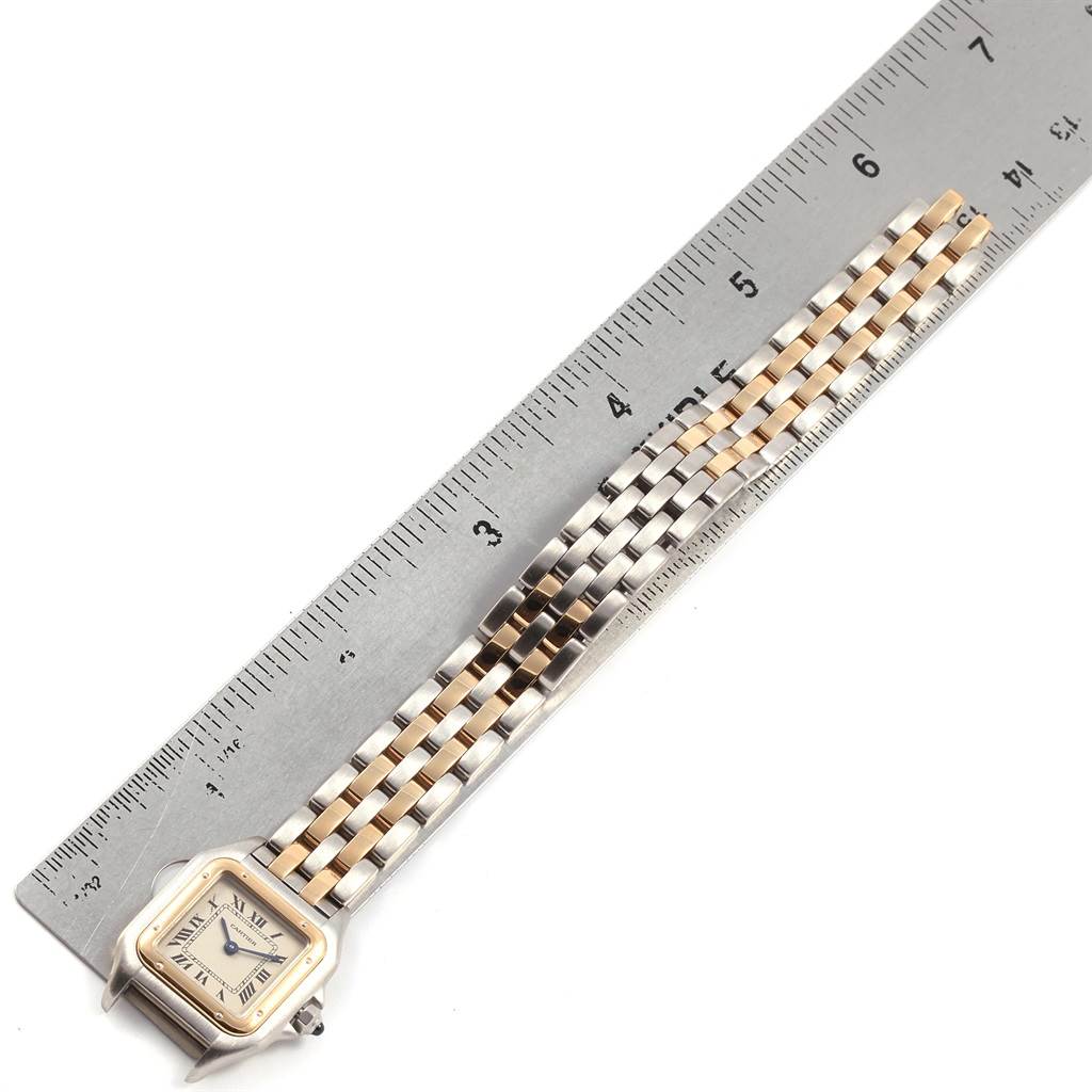 The image shows a Cartier Panthere W25029B6 Women
s Stainless Steel Silver Dial W25029B6 Women
s Stainless Steel Silver Dial watch laying next to a ruler, highlighting its face, bracelet, and clasp.