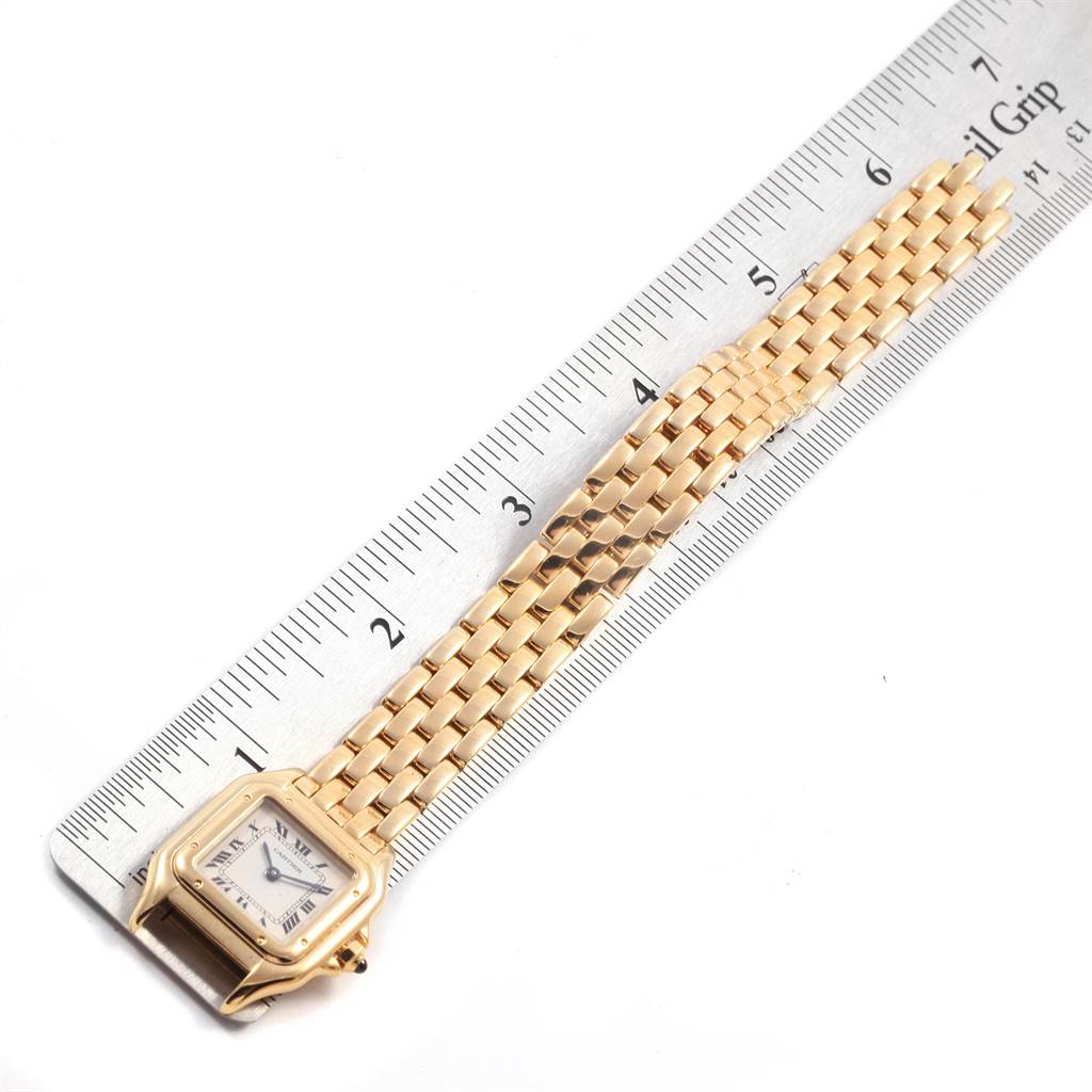 The Panthere model by Cartier is shown lying flat on a ruler with both the watch face and band visible.