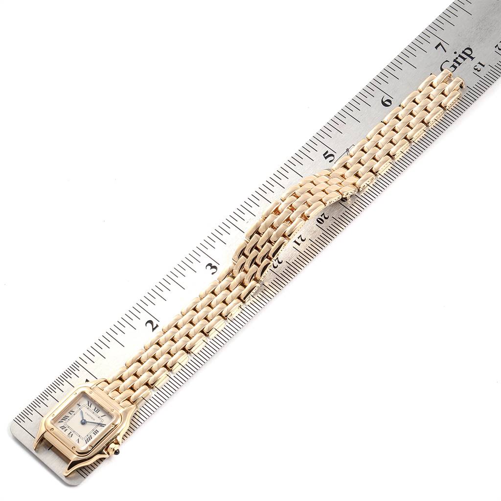This image shows a top-down view of a Cartier Panthère watch with a metal band placed over a ruler for length measurement.