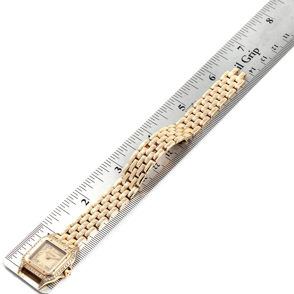The image shows a top view of a Cartier Panthere WF3072B9 Women's Yellow Gold Beige Dial WF3072B9 Women's Yellow Gold Beige Dial watch with its gold bracelet laid against a ruler.