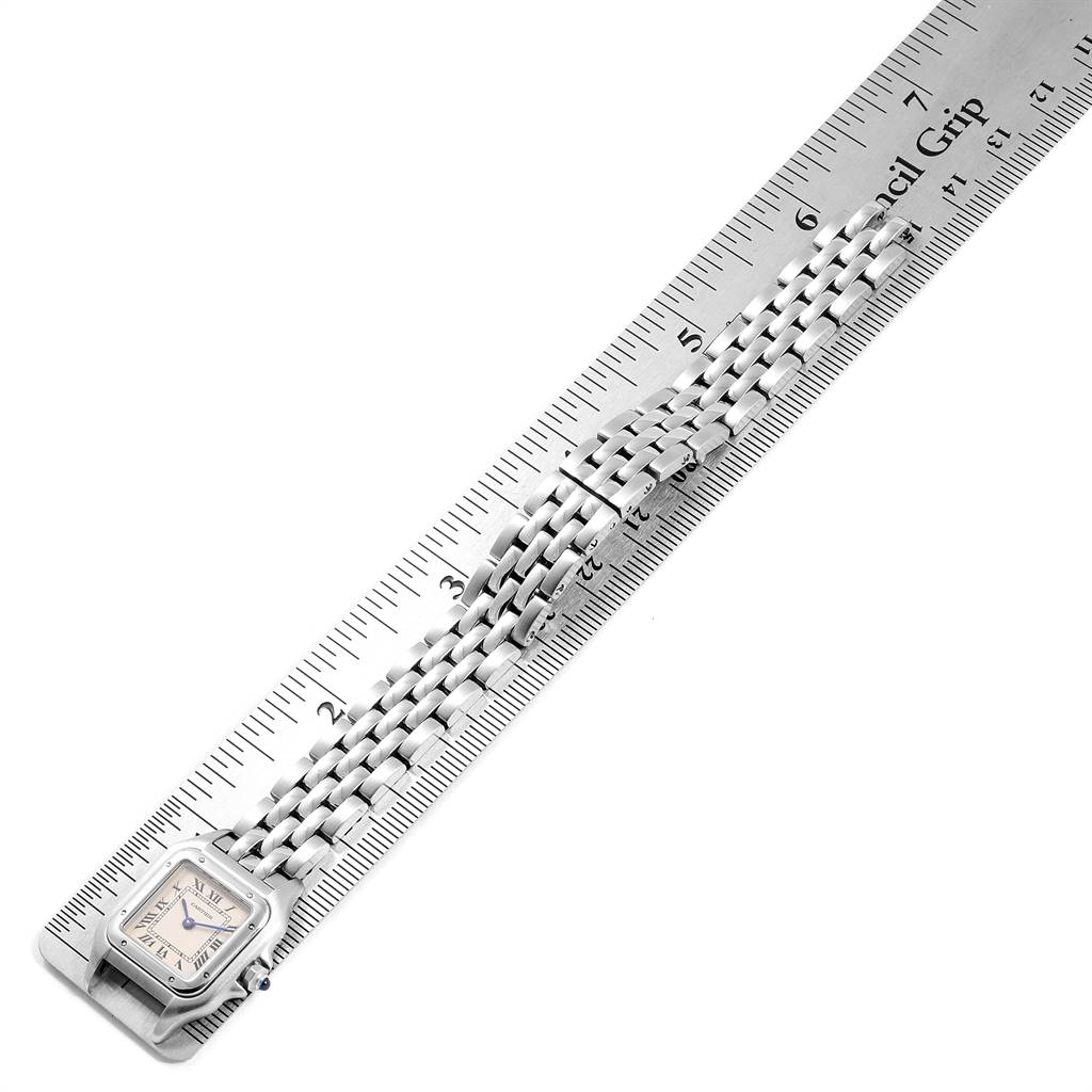 This image shows a flat, overhead view of a Cartier Panthère watch with its bracelet extended alongside a ruler.