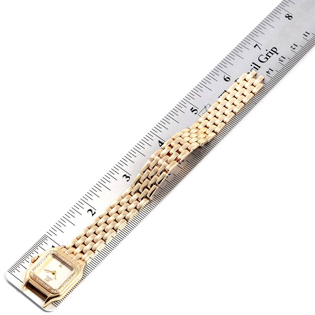 The image shows the Panthère model watch by Cartier from a top view, displaying its face and gold bracelet placed next to a ruler.
