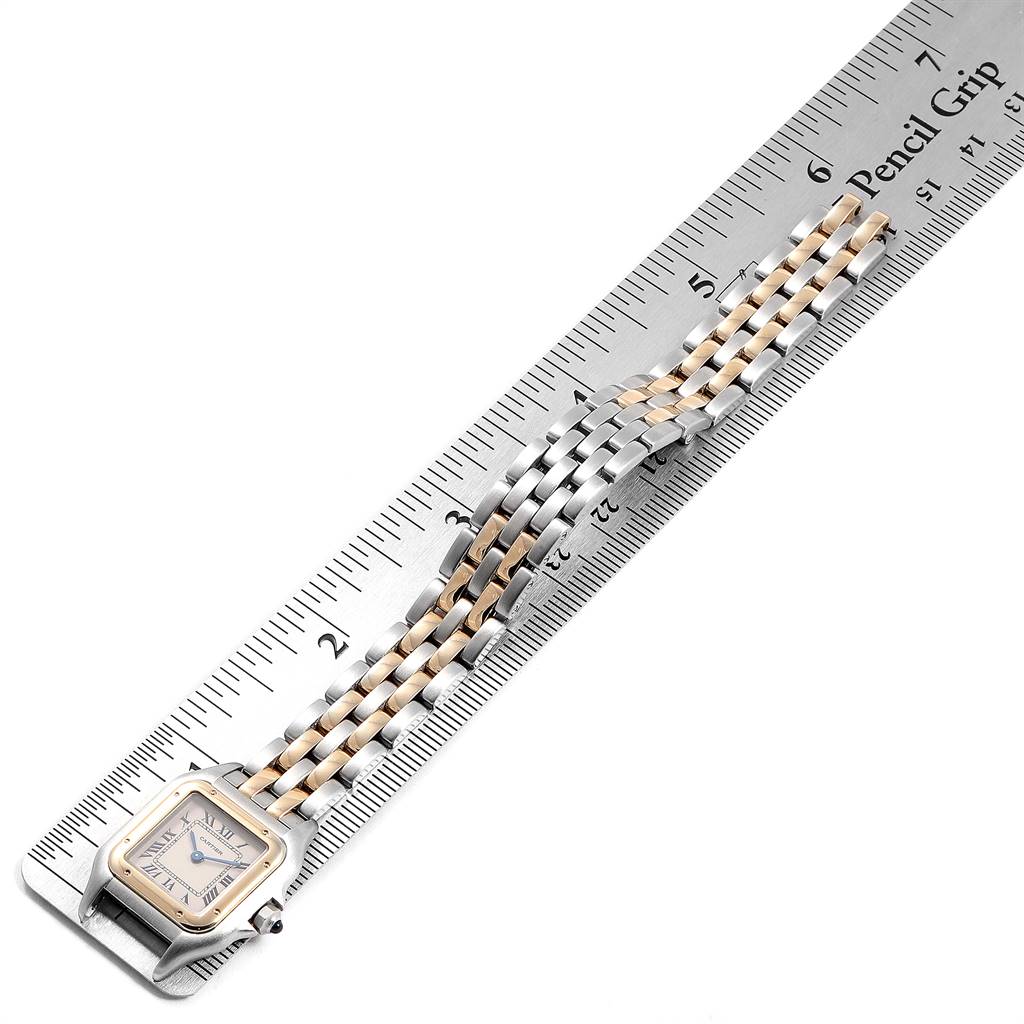 The image shows a Cartier Panthère watch placed at an angle on a ruler, highlighting its bracelet and face.