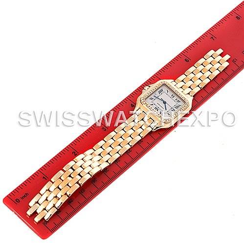 The image shows an overhead view of a Cartier Panthere Yellow Gold Silver Dial Yellow Gold Silver Dial watch with its gold bracelet placed alongside a red ruler.