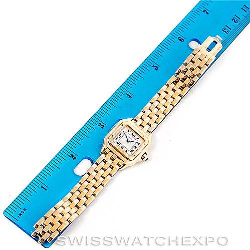 The image shows a Panthere model by Cartier laid flat next to a blue ruler, displaying the watch face and gold bracelet.