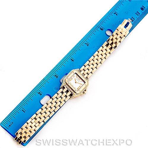 The image shows a Panthere model by Cartier placed next to a ruler for scale, displaying its watch face and gold bracelet in top view.