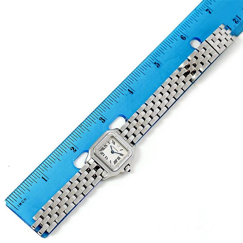 The image shows a top view of a Cartier Panthère watch with a metal link band placed next to a blue ruler for scale.