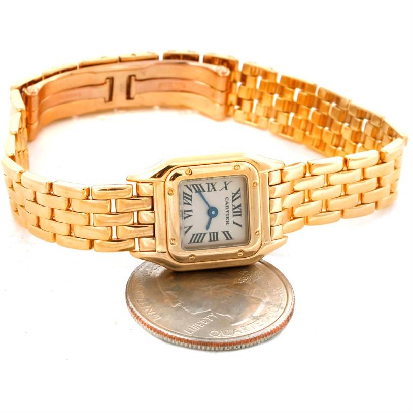 The Cartier Panthere W25034B9 Women's Yellow Gold Silver Dial W25034B9 Women's Yellow Gold Silver Dial watch is displayed at an angle showing its face, gold bracelet, and clasp, with a coin for scale.