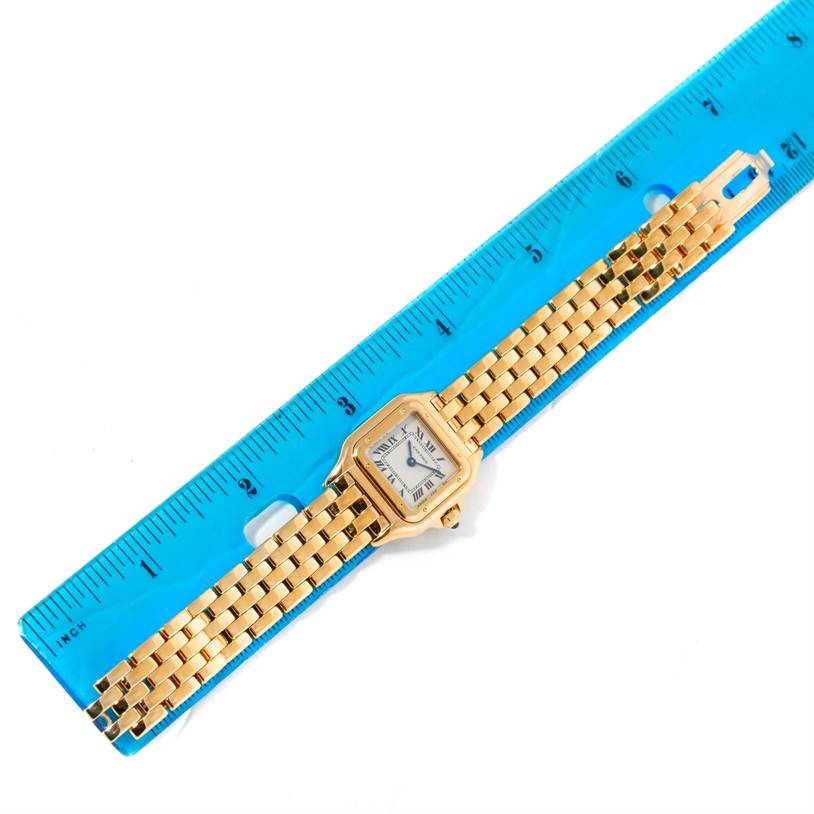 The image shows a Cartier Panthère watch laid flat and measured against a blue ruler, displaying the face and full gold bracelet.