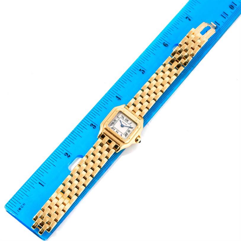 The image shows an overhead view of a Cartier Panthere W25022B9 Women's Yellow Gold Silver Dial W25022B9 Women's Yellow Gold Silver Dial model watch next to a blue ruler.