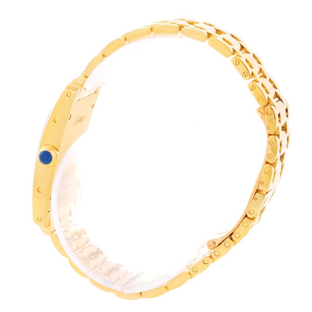 The image shows a side view of the Cartier Tank Americaine W26015K2 Women's Yellow Gold Silver Dial W26015K2 Women's Yellow Gold Silver Dial watch, highlighting its gold band and blue cabochon crown.