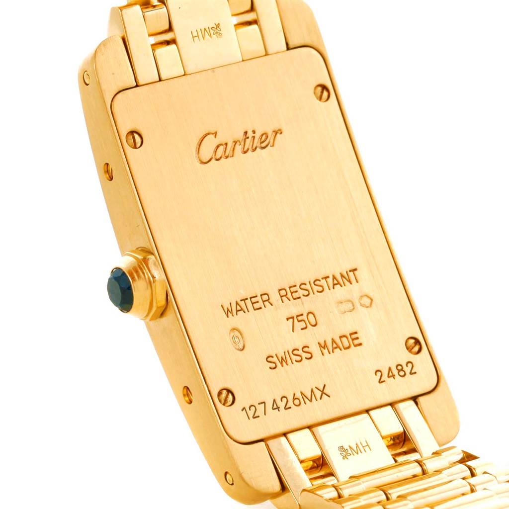 The image shows the back case and part of the bracelet of a Cartier Tank Américaine watch, highlighting its inscriptions and crown.