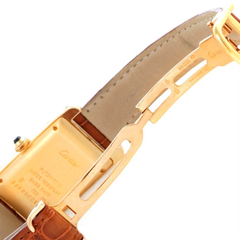 The image shows the clasp and back housing of the Tank Americaine by Cartier, highlighting its leather strap and gold detailing.