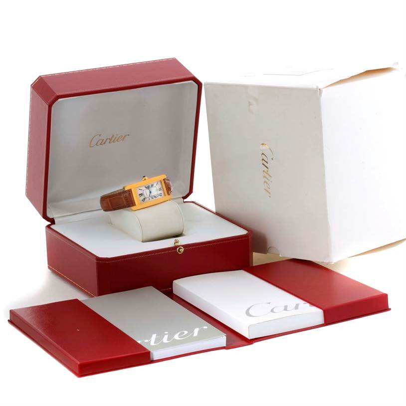 The image shows a Cartier Tank Americaine W2603556 Women's Yellow Gold Silver Dial W2603556 Women's Yellow Gold Silver Dial watch in its open box, along with an outer cardboard box and accompanying booklets.
