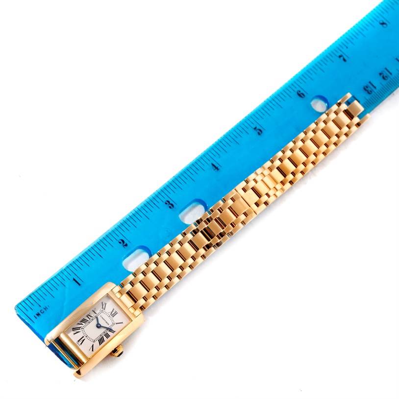 The image shows a Cartier Tank Americaine W26015K2 Women's Yellow Gold Silver Dial W26015K2 Women's Yellow Gold Silver Dial watch laid flat alongside a blue ruler for measurement.