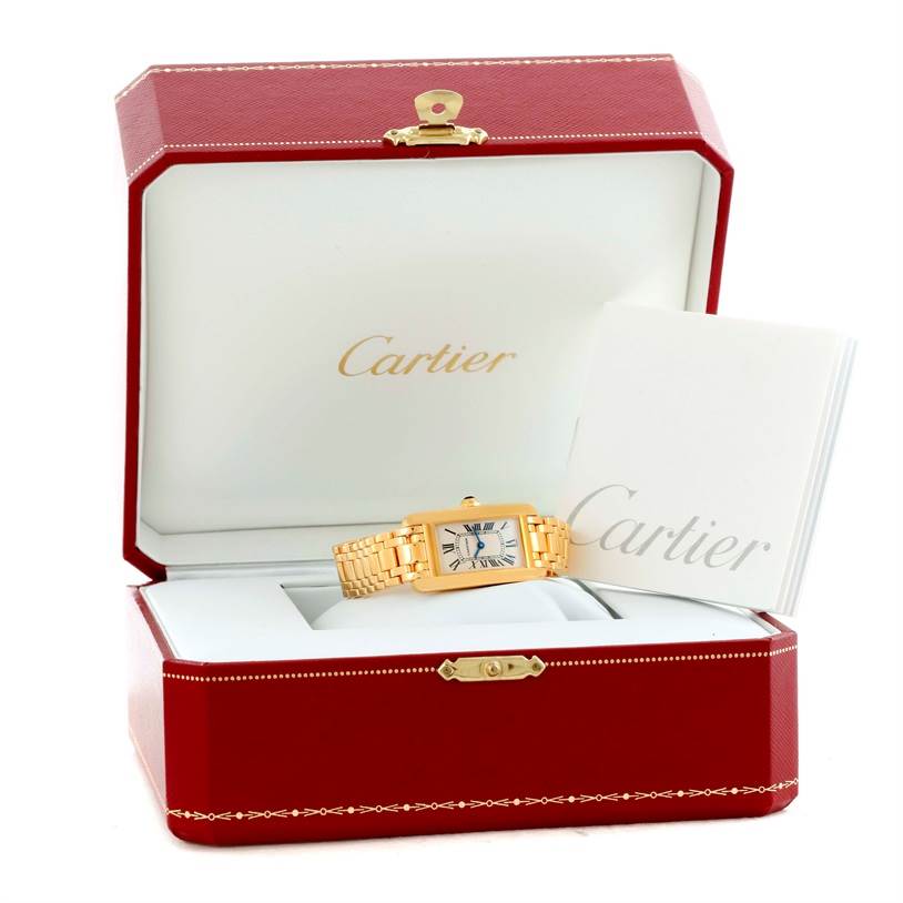 The Cartier Tank Americaine W26015K2 Women's Yellow Gold Silver Dial W26015K2 Women's Yellow Gold Silver Dial watch is shown in a red and white Cartier box with an accompanying booklet.