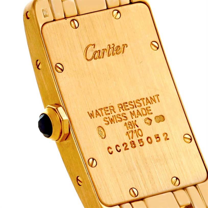 The image shows the back of a Cartier Tank Americaine W26015K2 Women's Yellow Gold Silver Dial W26015K2 Women's Yellow Gold Silver Dial watch, highlighting its gold casing and engraved details.