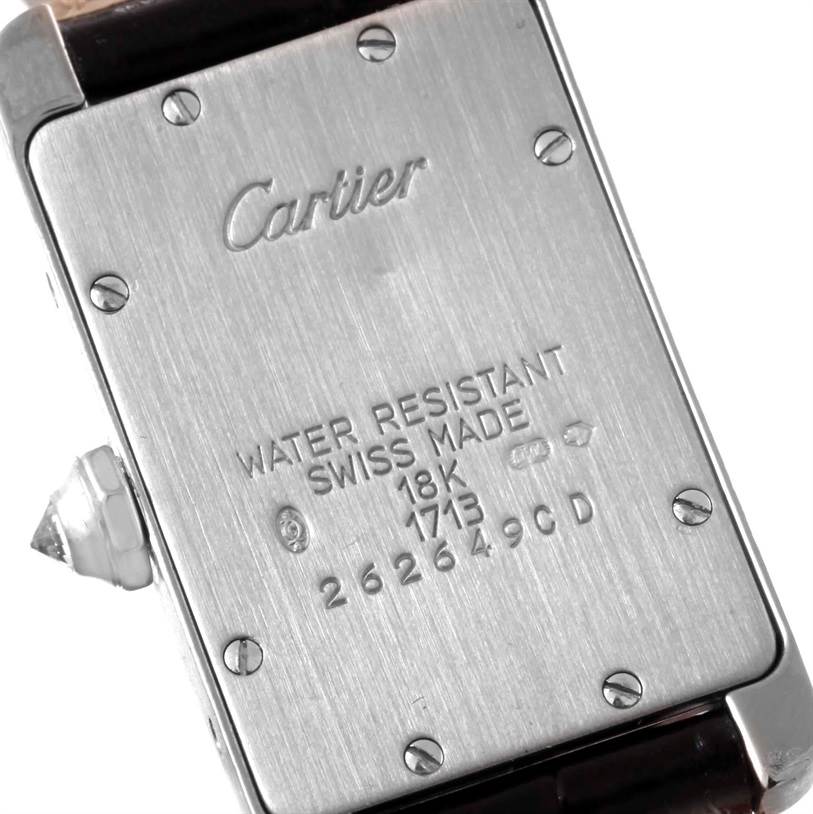 The image shows the back case of a Cartier Tank Americaine WB701851 Men's White Gold Silver Dial WB701851 Men's White Gold Silver Dial watch, displaying the brand name, material details, and serial numbers.