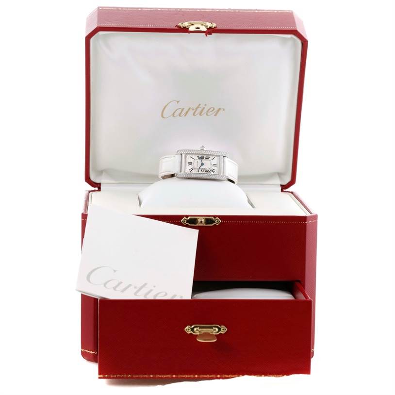 This image shows a Cartier Tank Américaine watch displayed in an open red Cartier box with an accompanying booklet.
